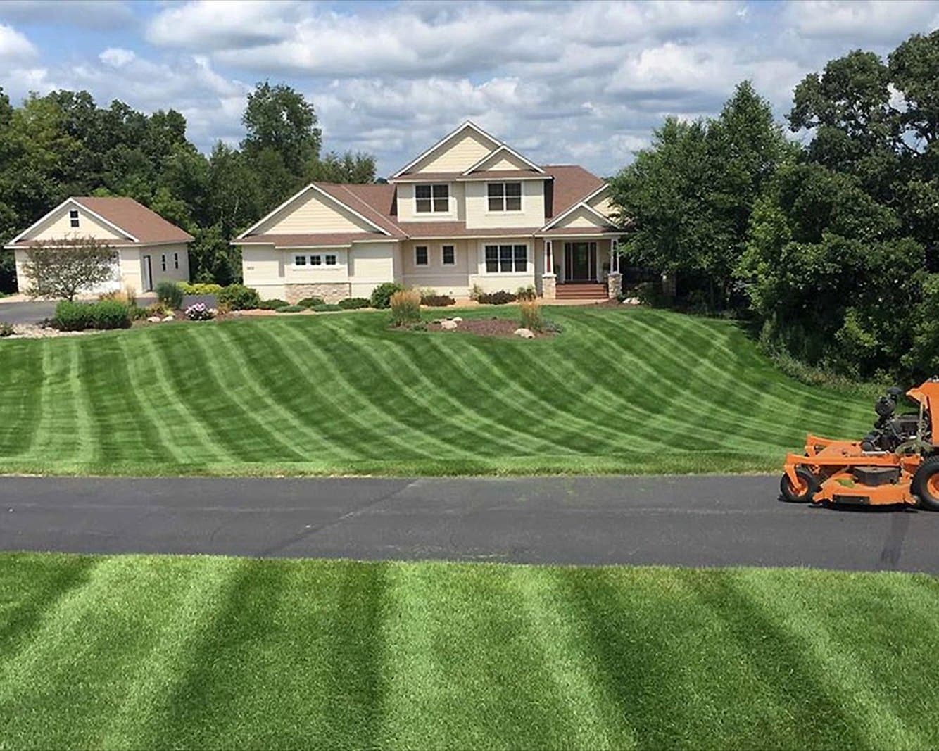 The Garten crew app on a phone, over a Meeks Mowing lawn
