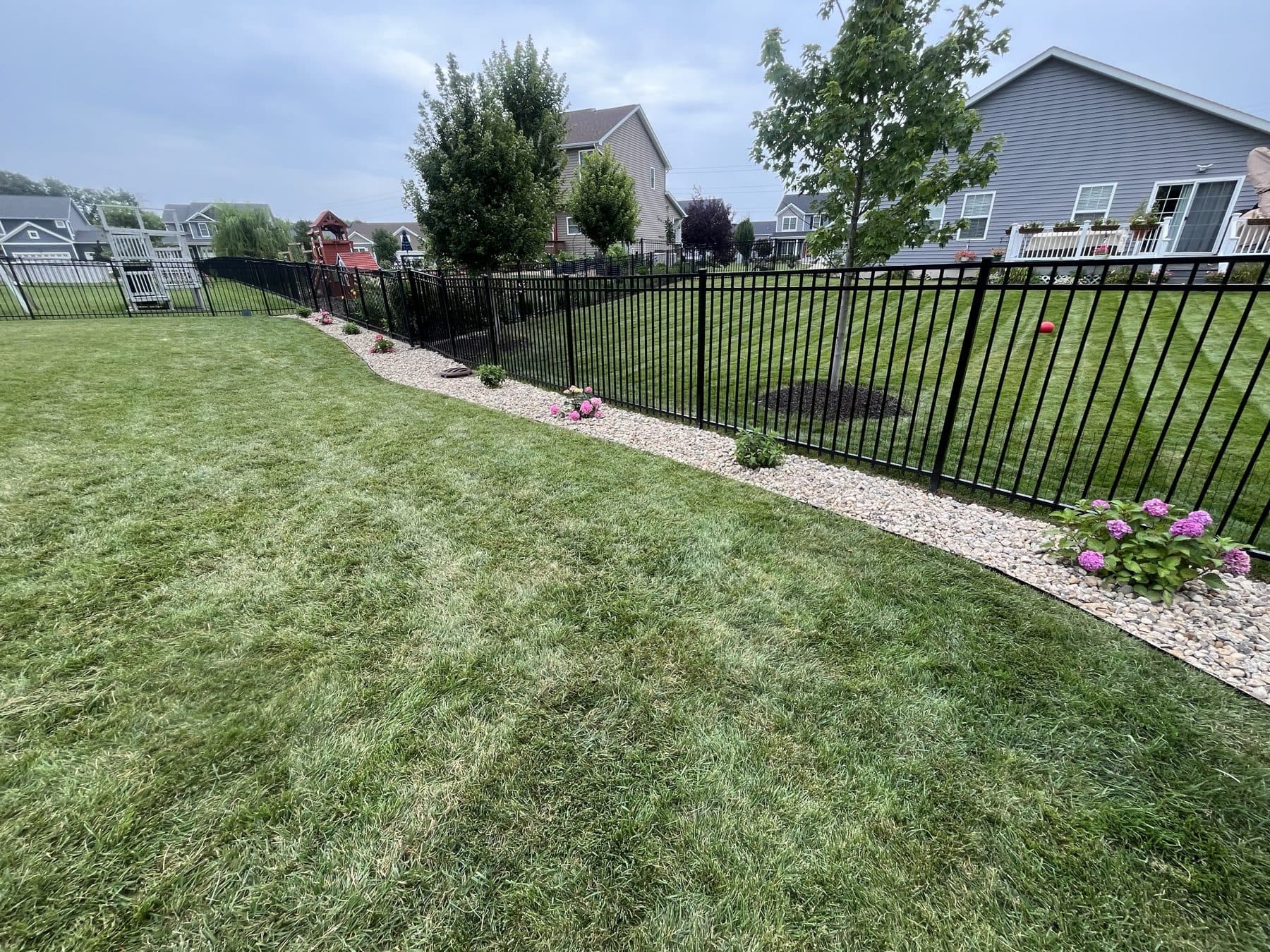 A striped lawn and rock bed by Meeks Mowing & Landscaping